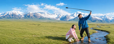 A couple using a bullet time selfie stick beside a mountain stream with snow-capped peaks in the background, showing the dynamic shooting effect outdoors.